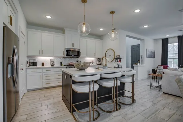 a kitchen with kitchen island granite countertop a sink and a refrigerator
