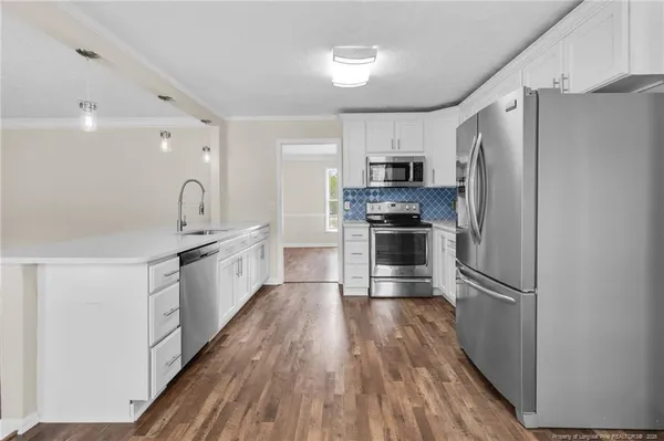 a kitchen with kitchen island granite countertop a refrigerator oven a sink and dishwasher