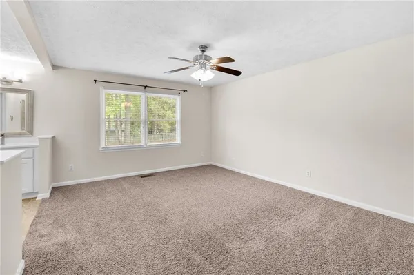 an empty room with windows and fan