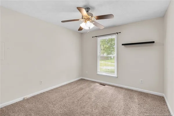 an empty room with a window and a ceiling fan