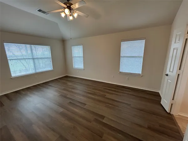 an empty room with wooden floor and windows