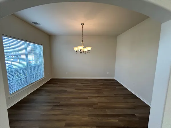 a view of an empty room with wooden floor and a fireplace