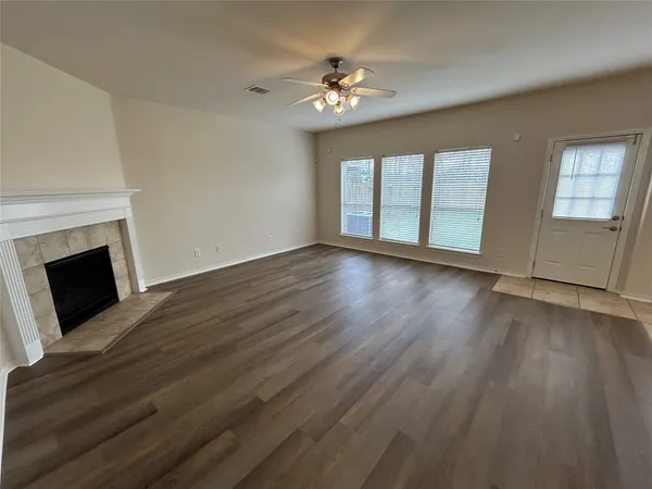 a view of an empty room with wooden floor fireplace and a window