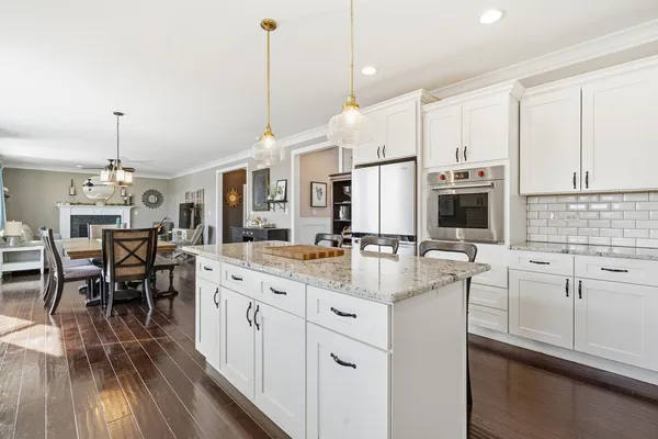 a kitchen with stainless steel appliances granite countertop a refrigerator a sink dishwasher a stove and white cabinets with wooden floor