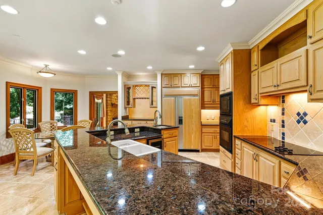 a kitchen with stainless steel appliances granite countertop a sink and a refrigerator