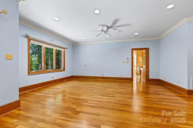a view of an empty room with window and wooden floor