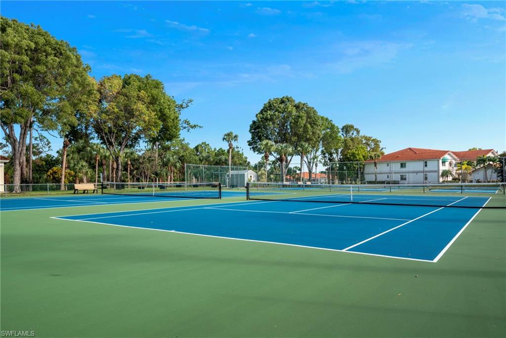 379 Gabriel Circle, Unit 2304 Naples, FL 34104 - Photo 23 of 23 a view of a tennis ground with large trees