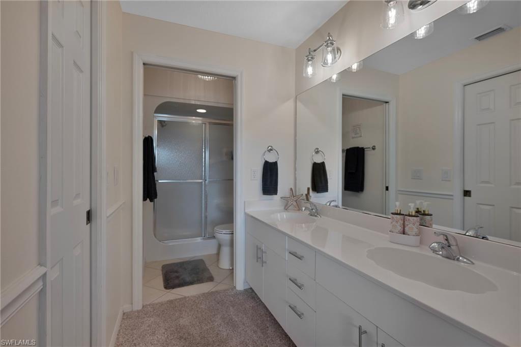 379 Gabriel Circle, Unit 2304 Naples, FL 34104 - Photo 10 of 23 a bathroom with a double vanity sink mirror double and shower