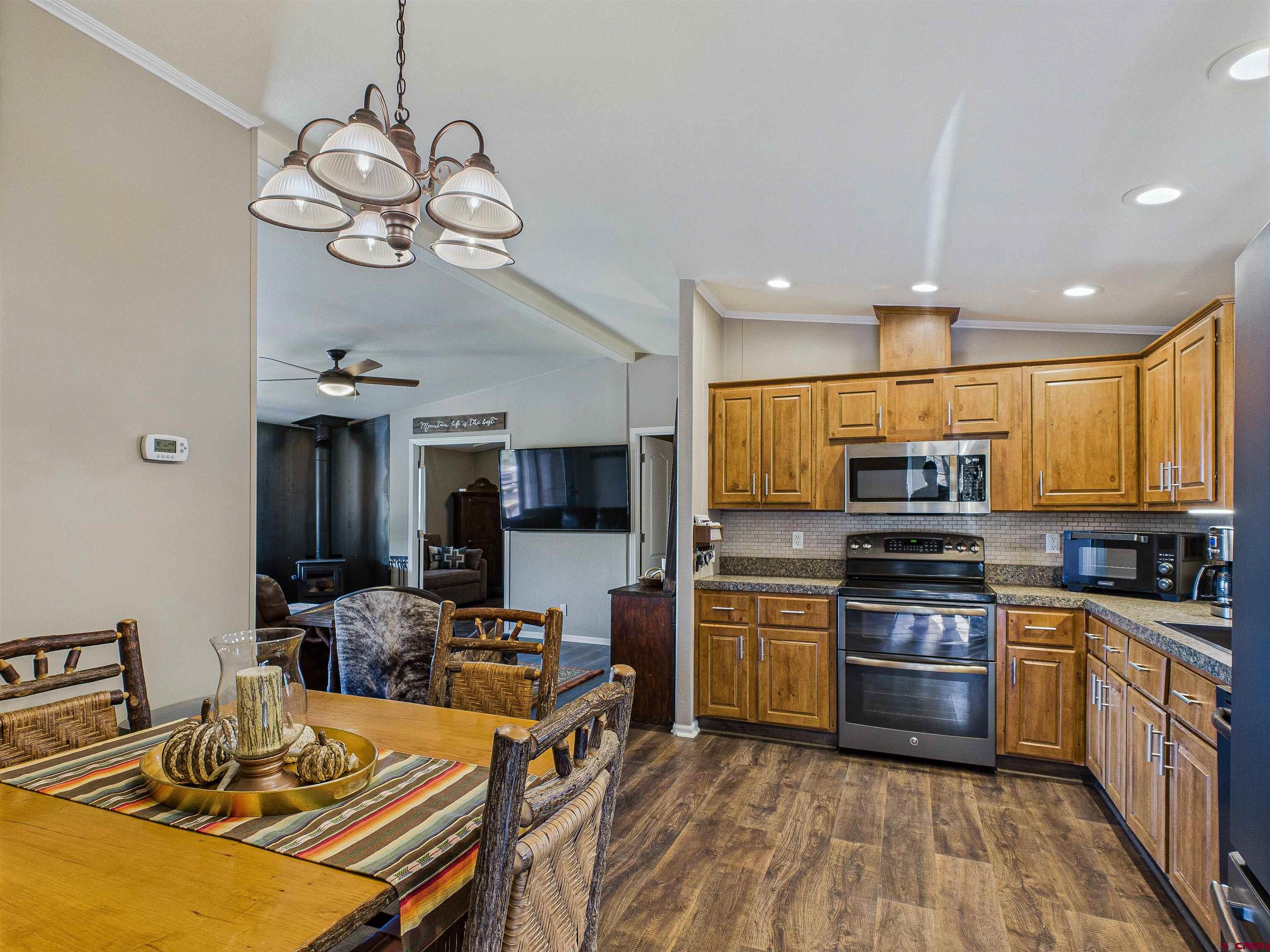 21578 Highway 65 Cedaredge, CO 81413 - Photo 28 of 45 a kitchen with a refrigerator a stove top oven a sink dishwasher and a dining table with wooden floor