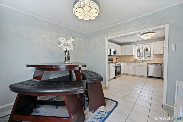 a living room with stainless steel appliances furniture a rug and a kitchen view