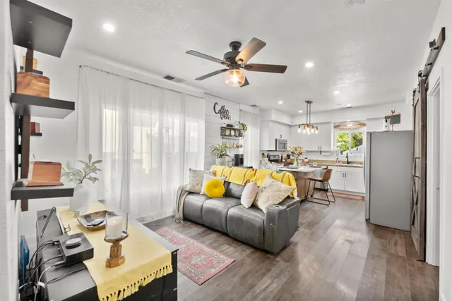 a kitchen with stainless steel appliances kitchen island granite countertop a refrigerator a stove a sink dishwasher and white cabinets with wooden floor