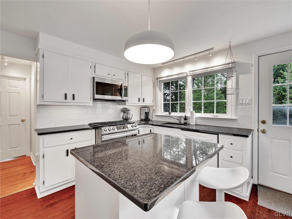 16 Hewett Road Cheltenham, PA 19095 - Photo 4 of 19 a kitchen with stainless steel appliances granite countertop a sink dishwasher a microwave oven with a dining table and chairs with wooden floor