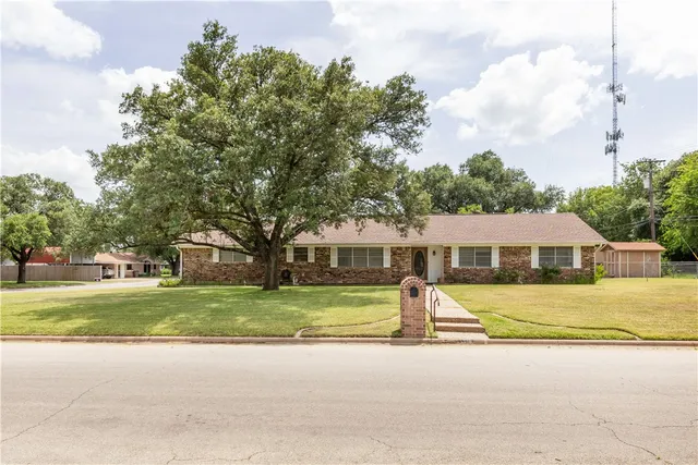 a view of a house with a big yard and large trees