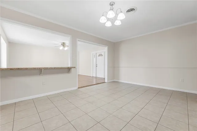 an empty room with chandelier fan and window