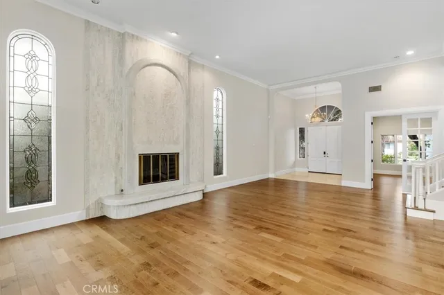 a view of an empty room with window and wooden floor