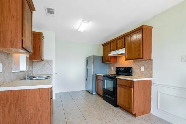a kitchen with stainless steel appliances granite countertop a stove a sink and a refrigerator