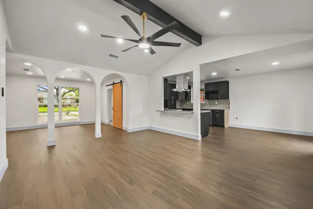 a view of a big room with wooden floor a ceiling fan and windows
