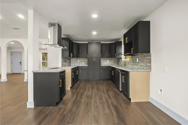 a large kitchen with stainless steel appliances kitchen island a large counter top and wooden floors