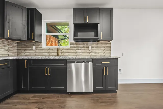 a kitchen with granite countertop a stove a microwave a sink and cabinets