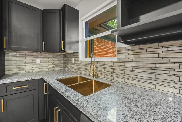 a bathroom with a granite countertop sink and a window