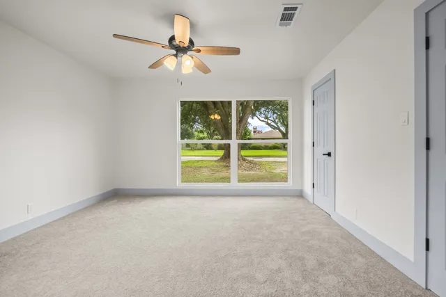 an empty room with windows and fan