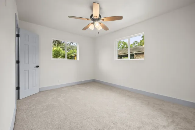 an empty room with windows and fan