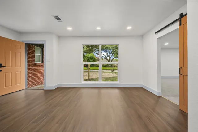 a view of an empty room with wooden floor and a window