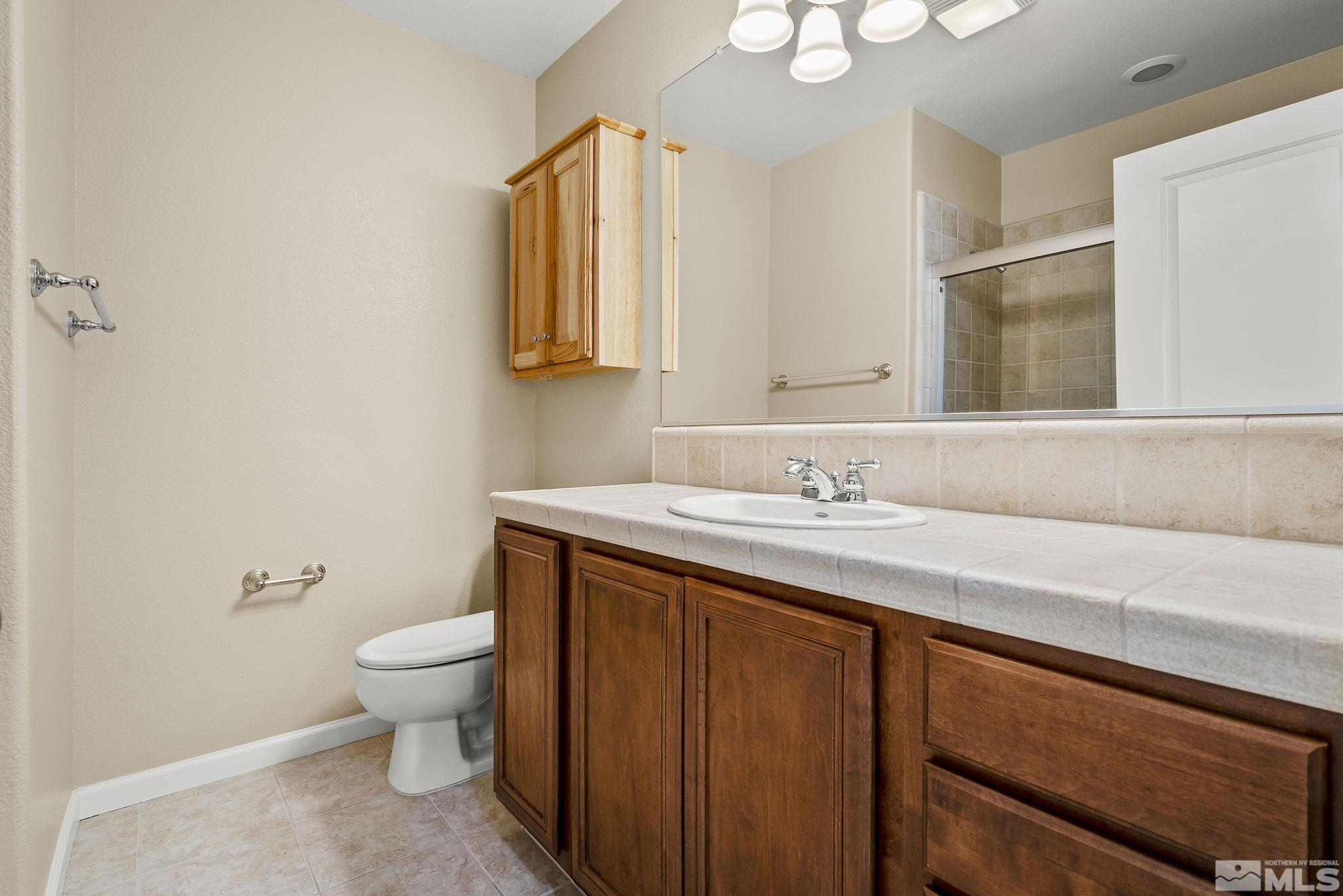 7688 Stone Bluff Way Reno, NV 89523 - Photo 21 of 26 a bathroom with a granite countertop sink a toilet and a mirror