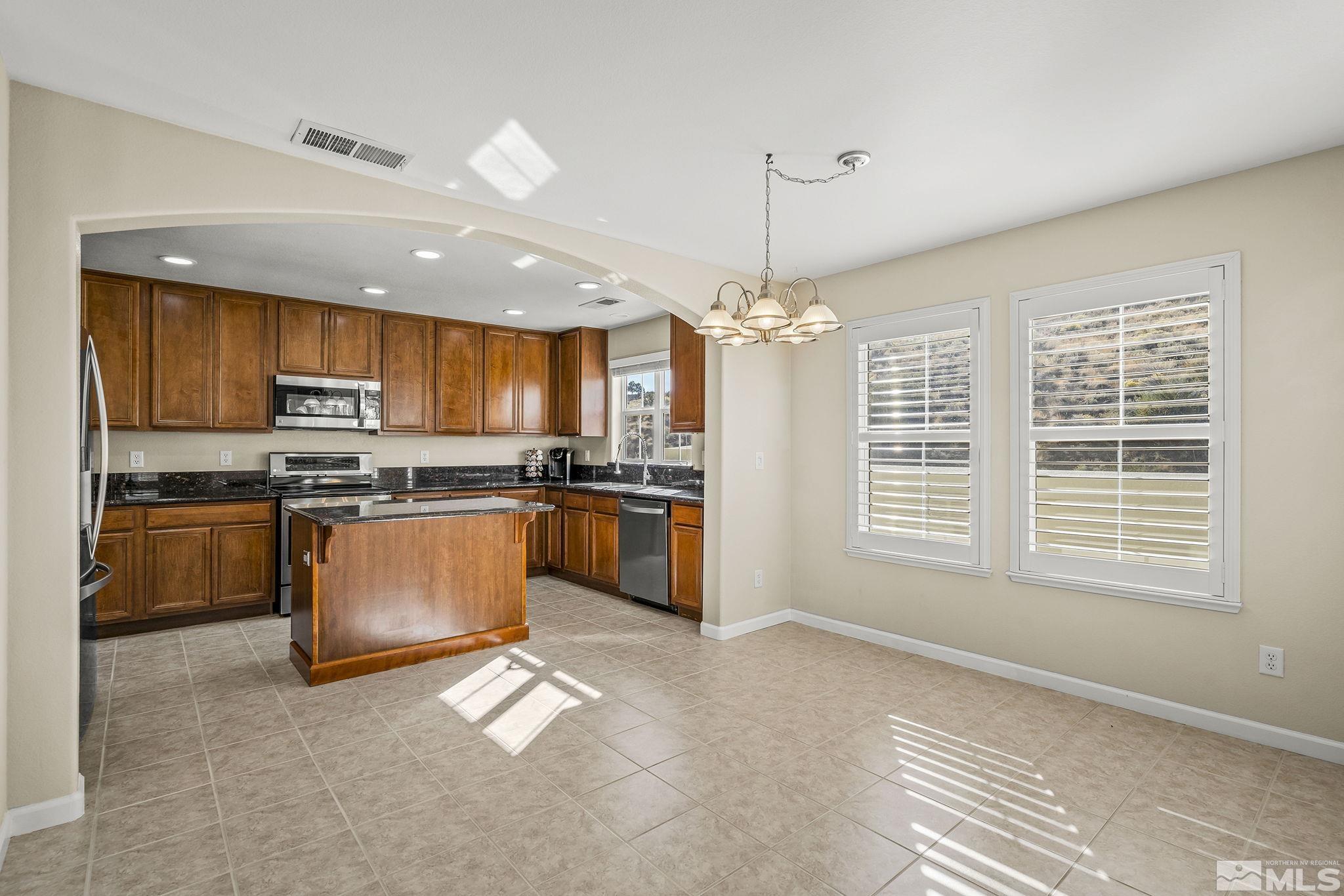 7688 Stone Bluff Way Reno, NV 89523 - Photo 7 of 26 a kitchen with stainless steel appliances granite countertop a stove top oven a sink dishwasher a dining table and chairs with wooden floor