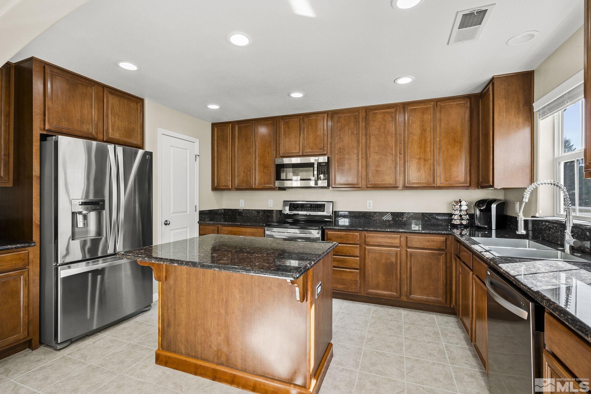 7688 Stone Bluff Way Reno, NV 89523 - Photo 8 of 26 a kitchen with stainless steel appliances granite countertop a refrigerator a sink a stove a microwave and island