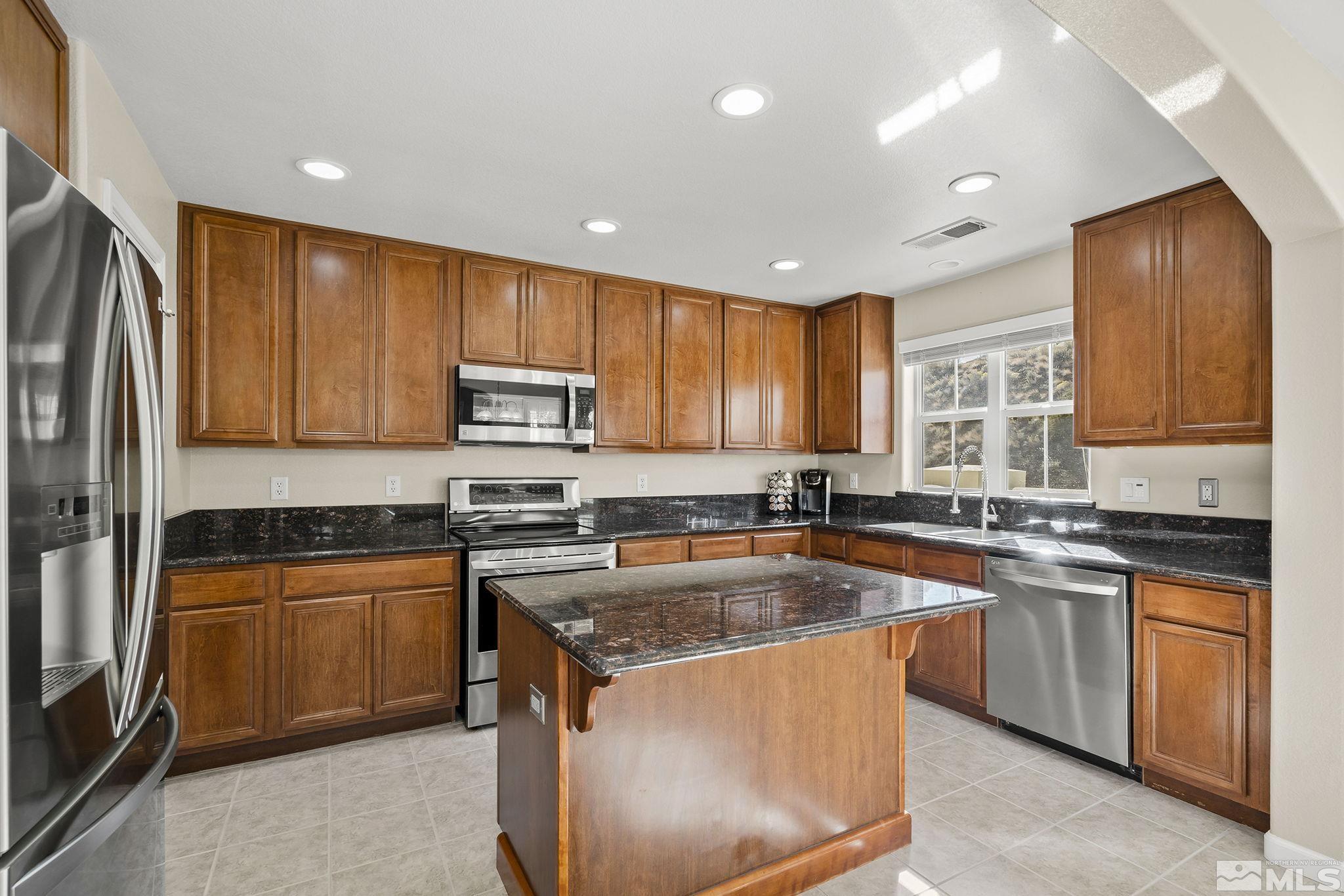 7688 Stone Bluff Way Reno, NV 89523 - Photo 9 of 26 a kitchen with stainless steel appliances granite countertop wooden cabinets sink and stove top oven