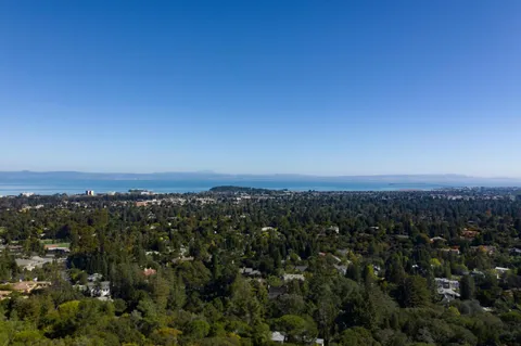a front view of a house with a yard and mountain view in back