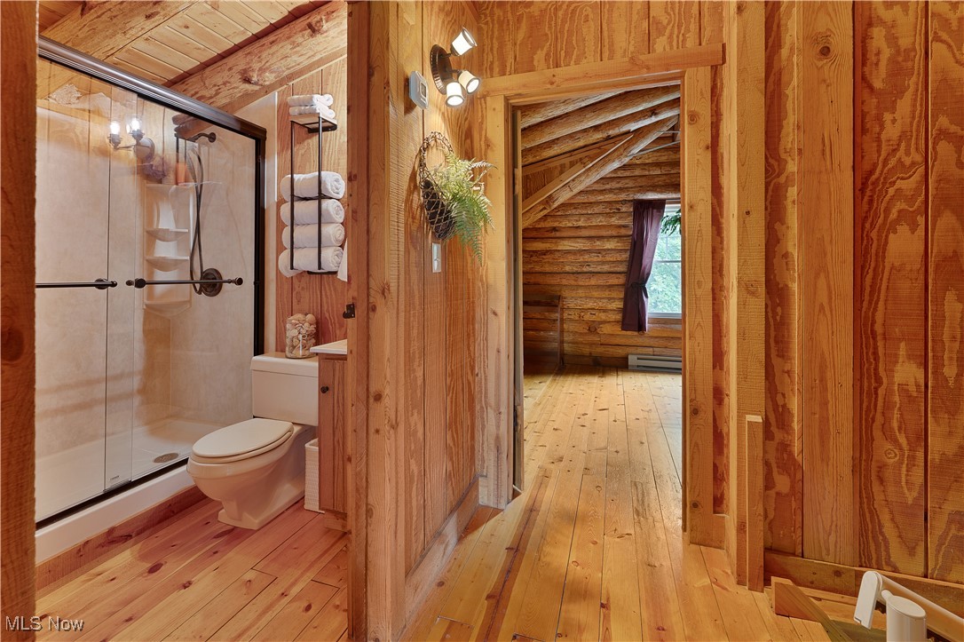 14 Clingan Road Struthers, OH 44471 - Photo 23 of 50 Bathroom featuring rustic walls, a shower stall, wood-type flooring, and a baseboard radiator