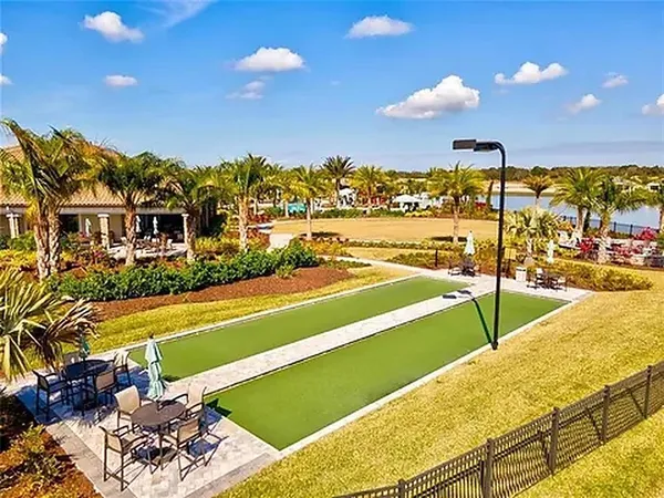 a view of a swimming pool with a table and chairs under palm trees