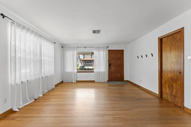 a view of a big room with wooden floor and windows