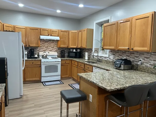 a kitchen with granite countertop a sink stove and refrigerator