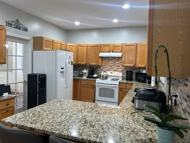 a kitchen with granite countertop a refrigerator and a stove top oven