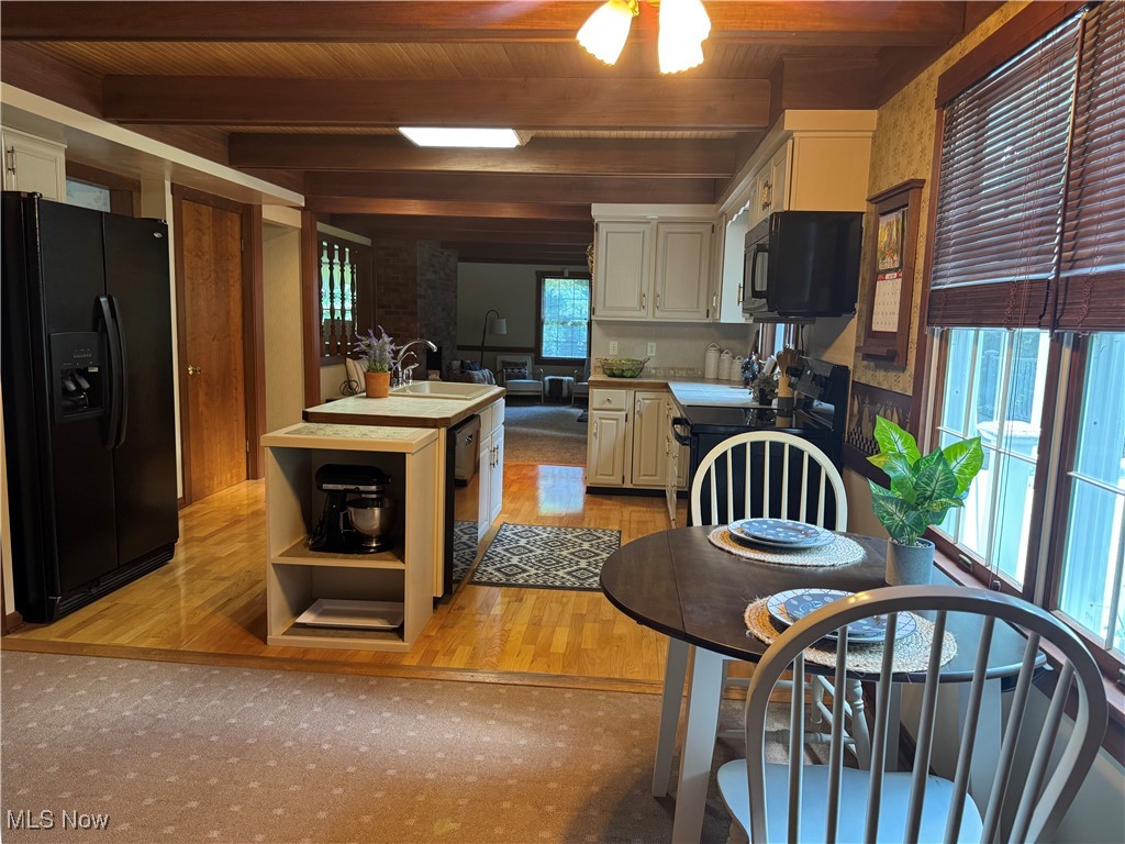 7345 Roller Road Salem, OH 44460 - Photo 14 of 50 Kitchen with black appliances, a wooden ceiling with exposed beams, light wood-style floors, a center island with sink, and open shelves