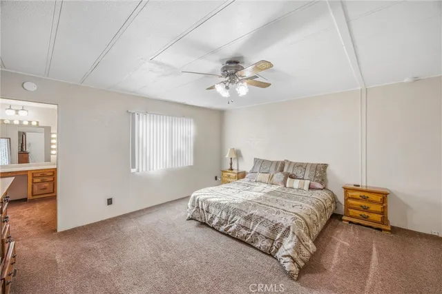 a bedroom with a bed a ceiling fan and a dresser