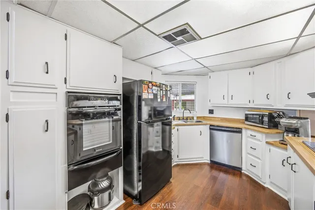 a kitchen with a refrigerator stainless steel appliances wooden floor and cabinets