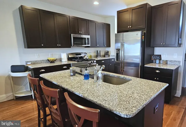 a kitchen with granite countertop a table chairs microwave and refrigerator