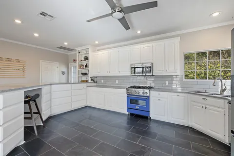a kitchen with kitchen island granite countertop a sink window and white stainless steel appliances