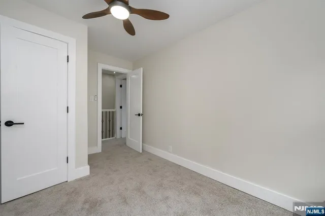 an empty room with a chandelier fan and closet area