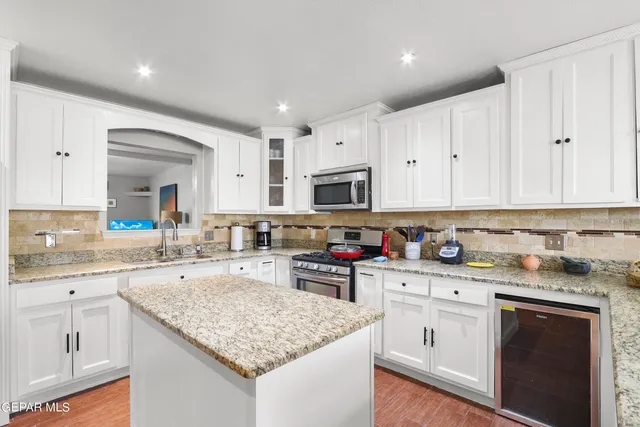 a kitchen with granite countertop white cabinets sink and stainless steel appliances