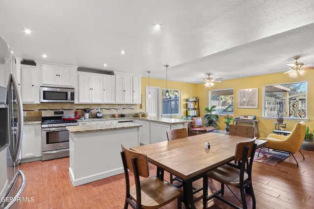 a large kitchen with kitchen island granite countertop lots of white cabinets appliances and furniture