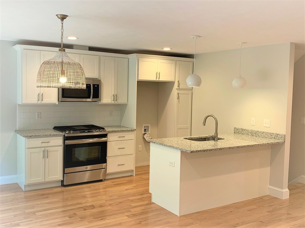 25 Shaker Road, Unit B Ayer, MA 01432 - Photo 2 of 16 a kitchen with stainless steel appliances granite countertop a sink a stove and a wooden floor