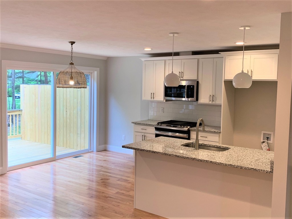 25 Shaker Road, Unit B Ayer, MA 01432 - Photo 4 of 16 a kitchen with granite countertop a stove a sink and a wooden floors