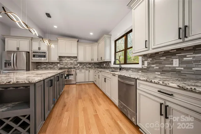 a large kitchen with stainless steel appliances granite countertop a stove sink and cabinets