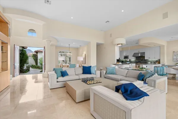 a living room with white couches and kitchen view with wooden floor