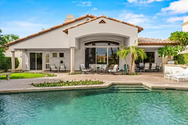 a view of a white house with a swimming pool table and chairs